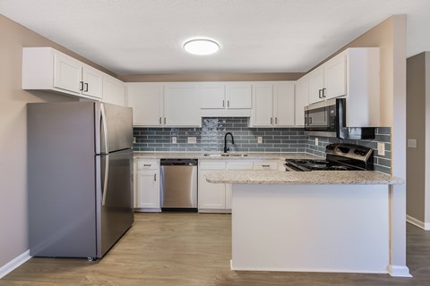 A kitchen with a refrigerator, microwave, and oven.