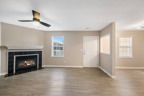 A living room with a fireplace and a ceiling fan.