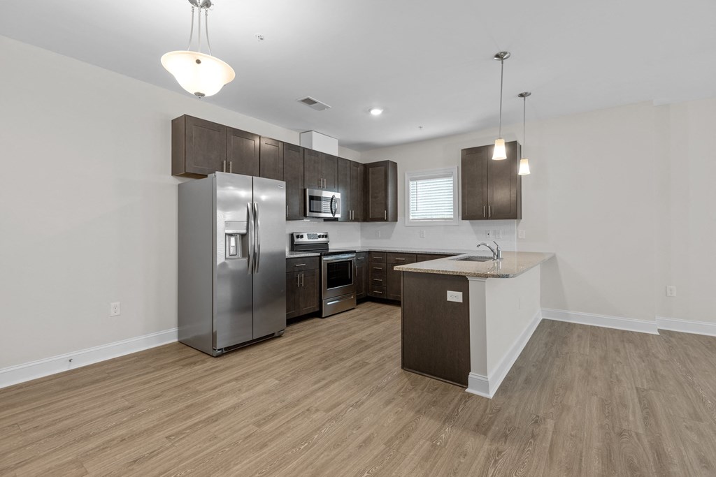 a kitchen with stainless steel appliances and wooden flooring in a new home