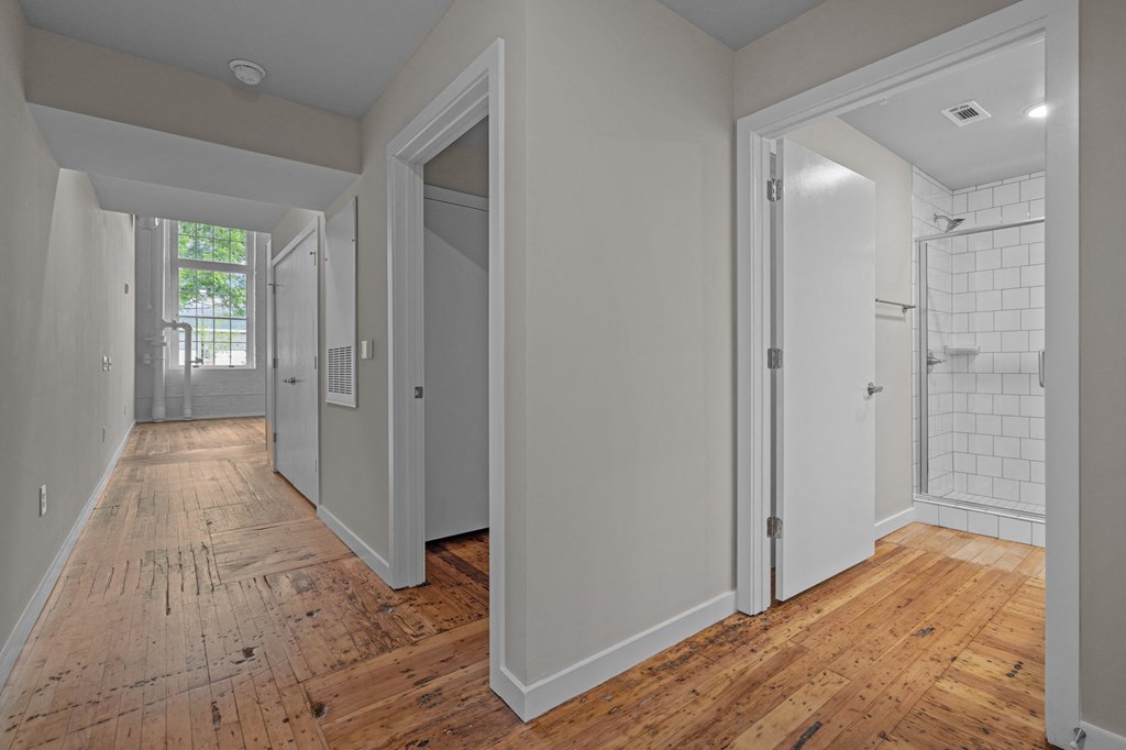 a renovated bedroom and hallway with wood floors and white walls
