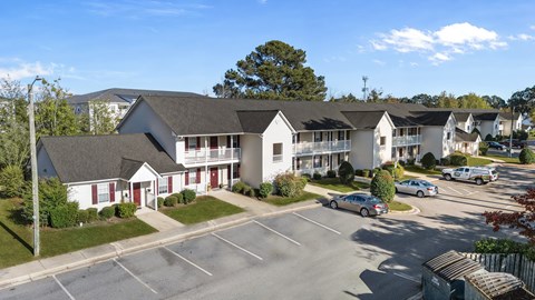 A parking lot in front of a building with a red door.at Spring Lake Apartments in Greenville, NC