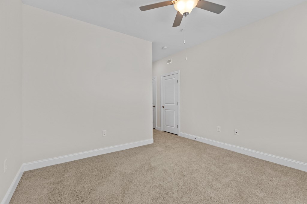 an empty living room with a ceiling fan and white walls