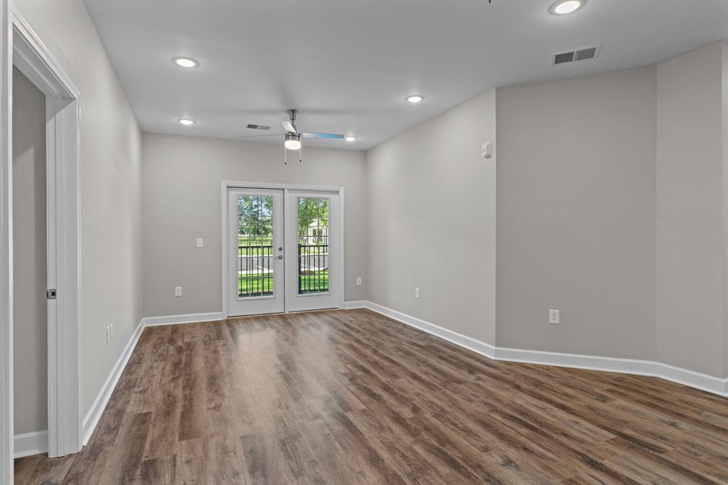 an empty living room with wood flooring and a door to a yard