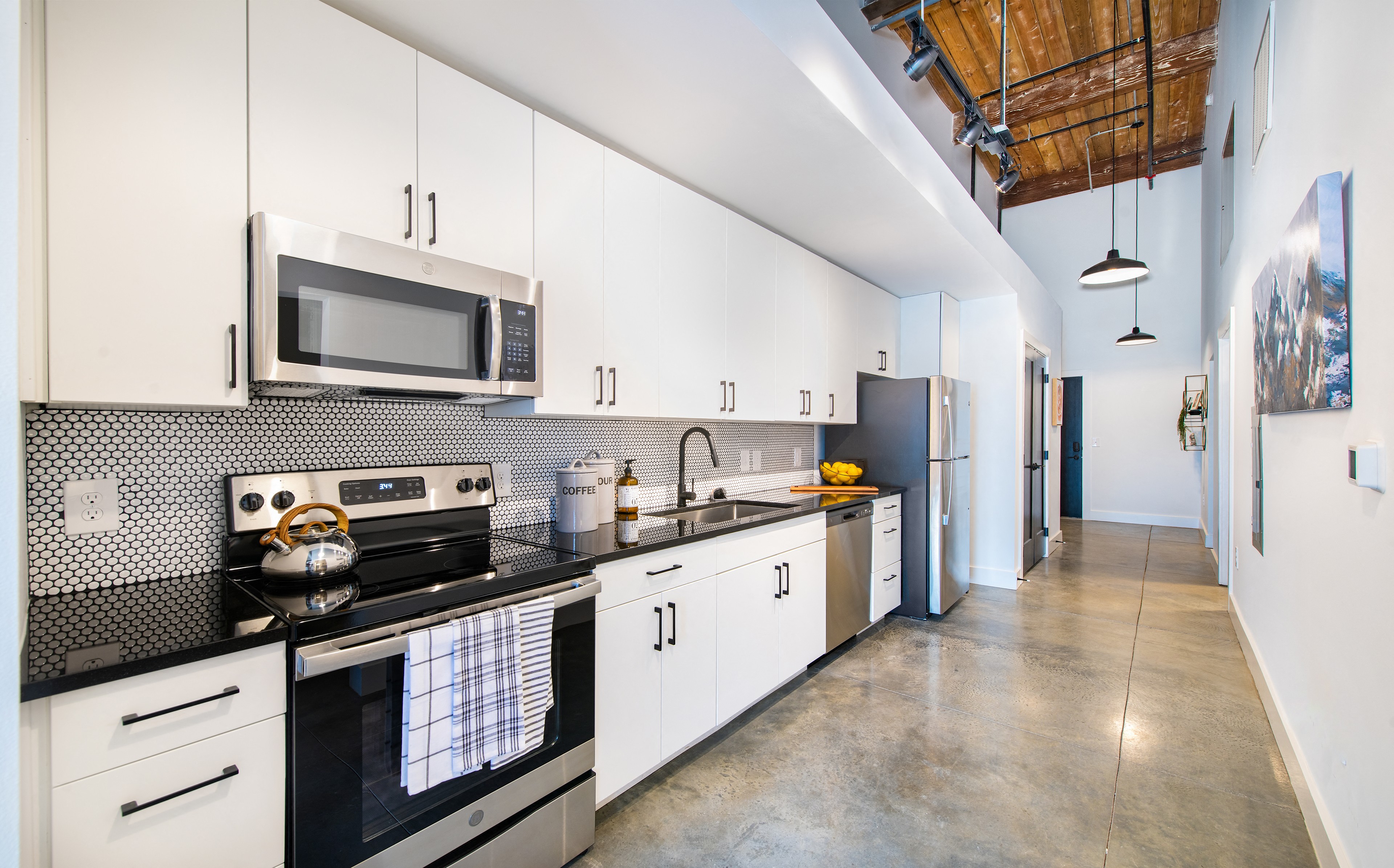 A modern kitchen with white cabinets and black countertops.