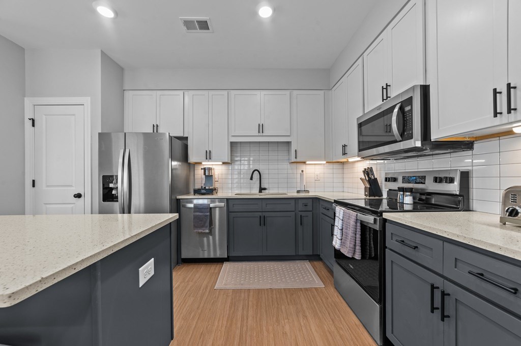A modern kitchen with dark grey cabinets and stainless steel appliances.