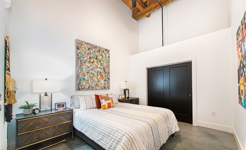 A bedroom with a large bed and a painting on the wall. at Judson Mill Lofts and The Jenny & Westervelt in Greenville, SC