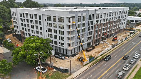 A large white building under construction with a crane in front of it.