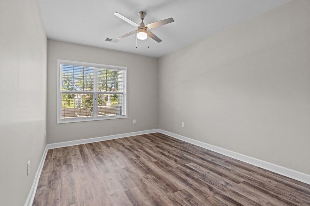 an empty bedroom with a window and a ceiling fan