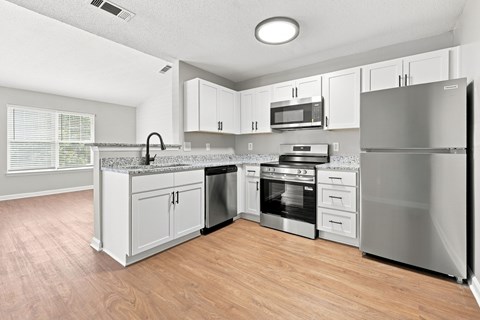 A kitchen with a refrigerator, oven, and microwave.