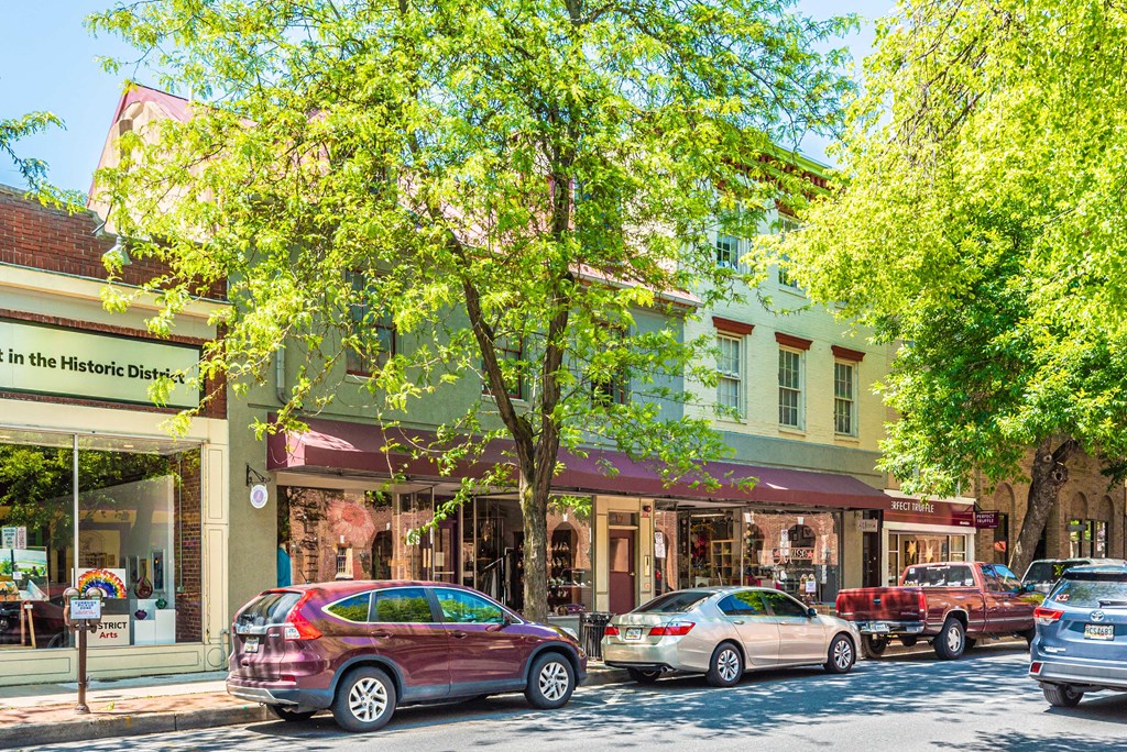 a city street with cars parked in front of shops