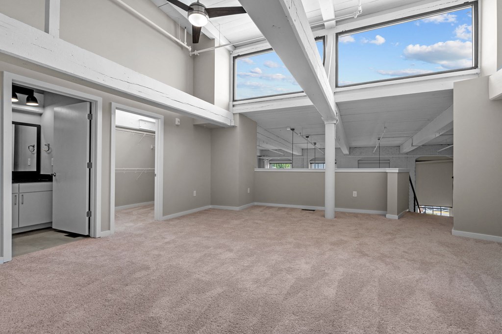 an empty living room with windows and a kitchen
