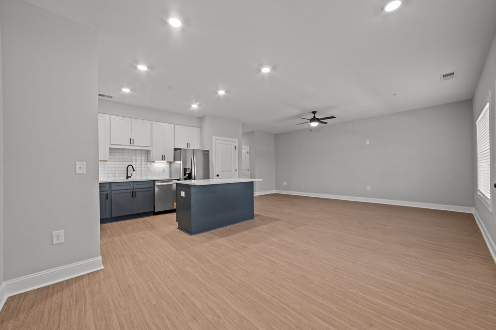 A spacious room with a kitchen area and wooden flooring.at Regency Townes, Winterville North Carolina