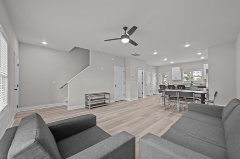 A living room with grey couches and a ceiling fan.