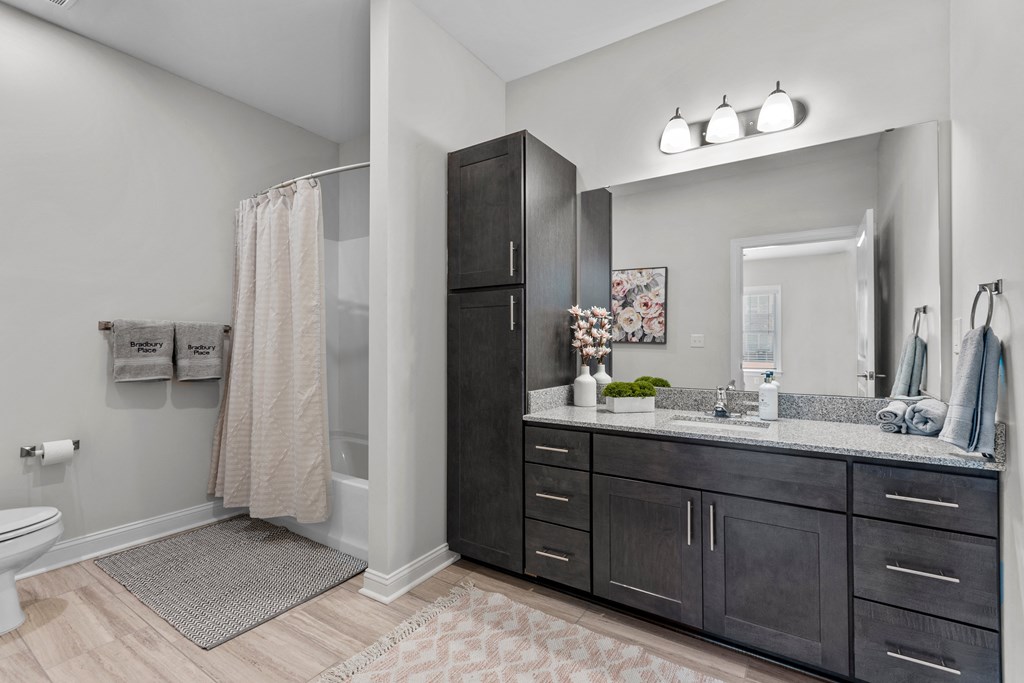 a bathroom with dark cabinets and a shower and a sink