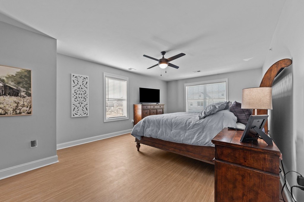 A bedroom with a bed, dresser, and a ceiling fan.