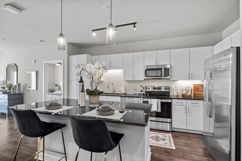 an open kitchen and dining area with white cabinets and stainless steel appliances