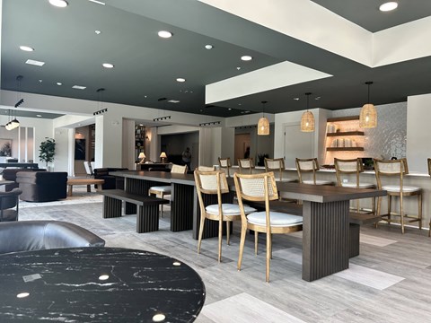 A modern dining room with a black marble table and wooden chairs.