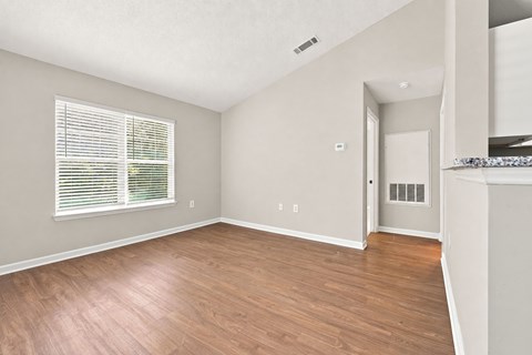 A room with wooden flooring and a window with blinds.