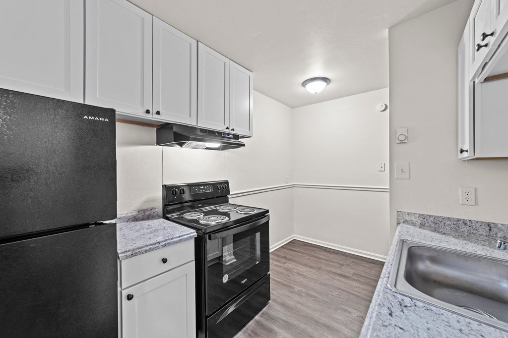 a kitchen with white cabinets and black appliances and a sink