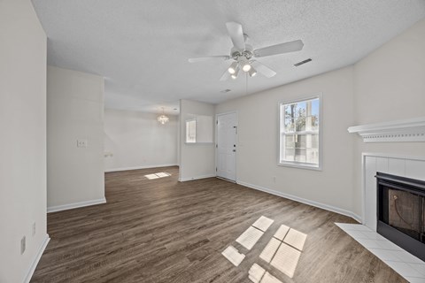 A living room with a fireplace and a ceiling fan.