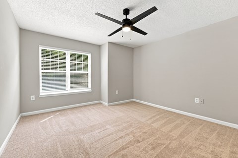 A room with a ceiling fan and a window with blinds.