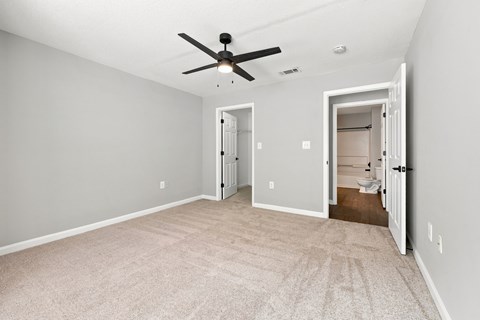 A room with a ceiling fan and two doors.