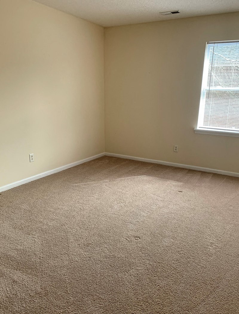 an empty room with carpet and a window