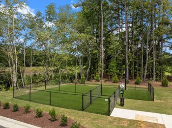 A tennis court surrounded by a fence and trees at Regency Townes in Greenville, NC