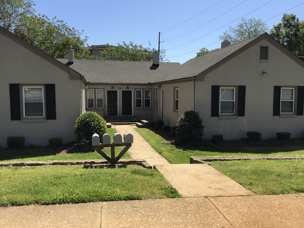 a white house with a sidewalk in front of a yard with a mailbox