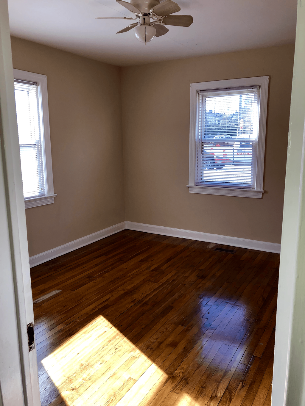 an empty room with wooden floors and a ceiling fan