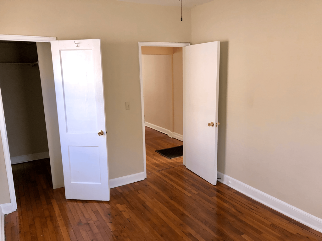 an empty room with three doors and a wood floor