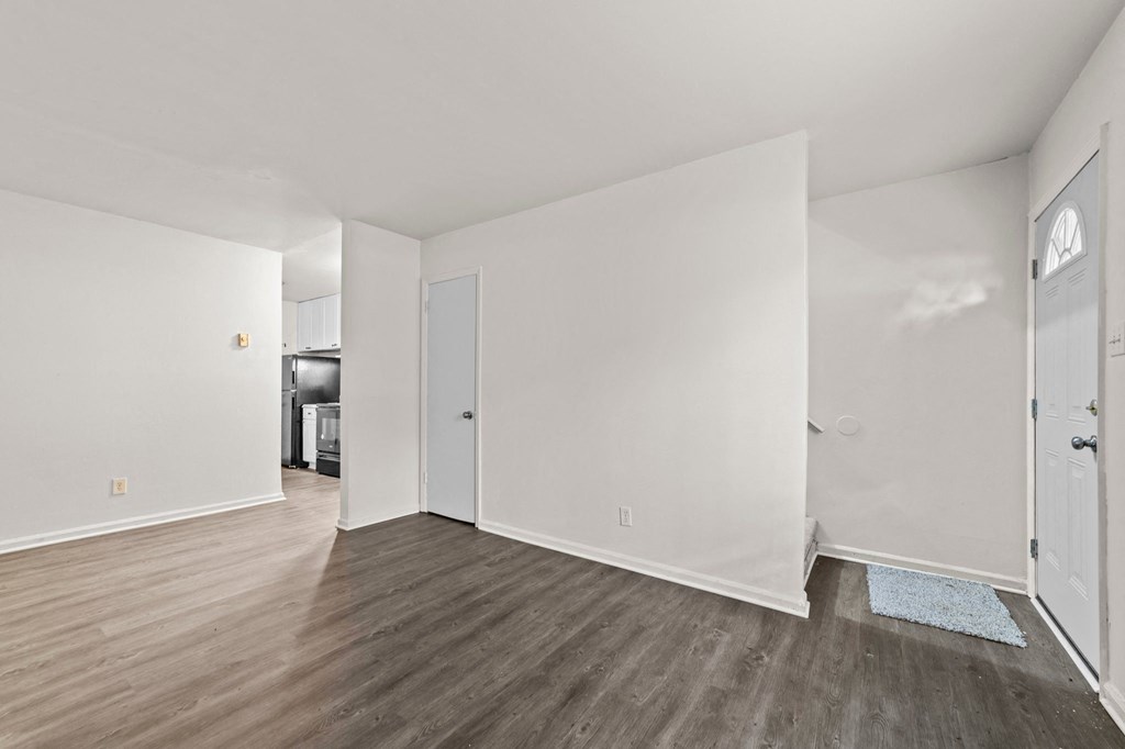 an empty living room with white walls and wood flooring