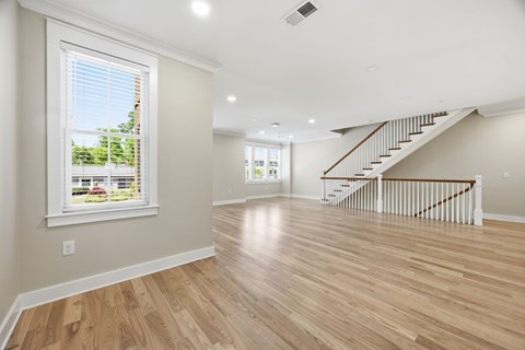 Open floor plan with hardwood floors and staircase at Adler Montford Park + Drexel Townes Apartments, Charlotte, North Carolina