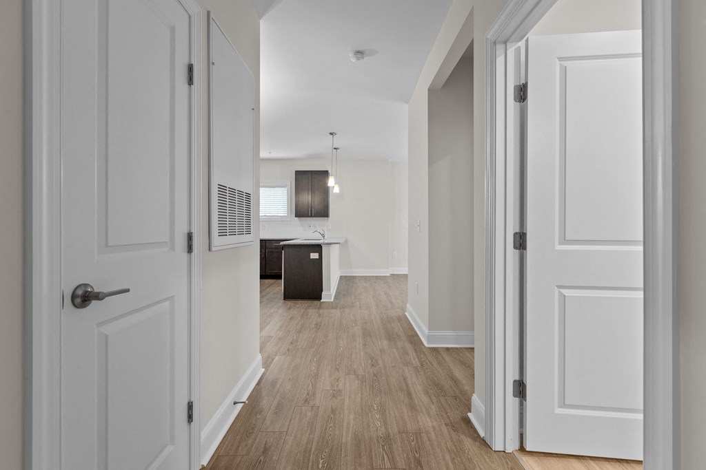 a renovated living room and kitchen with white walls and wood floors