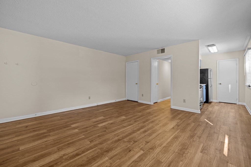 the living room and dining room of an apartment with wood flooring