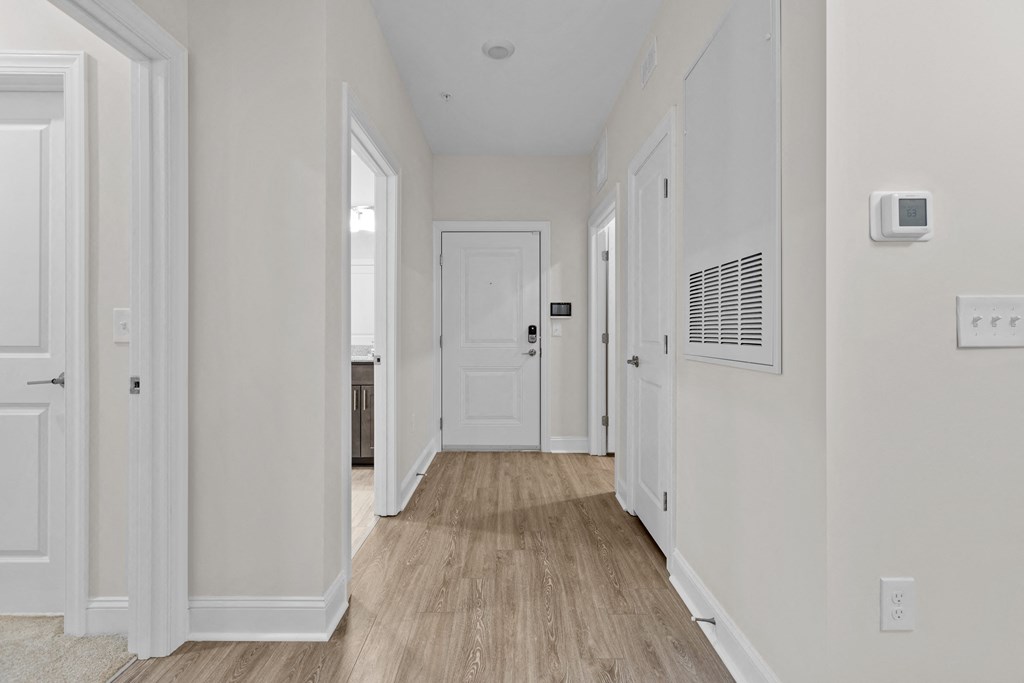 a hallway with white walls and wood floors and a white door