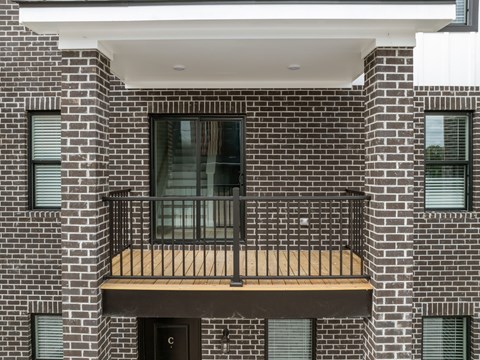 A balcony with a wooden railing and a glass door.