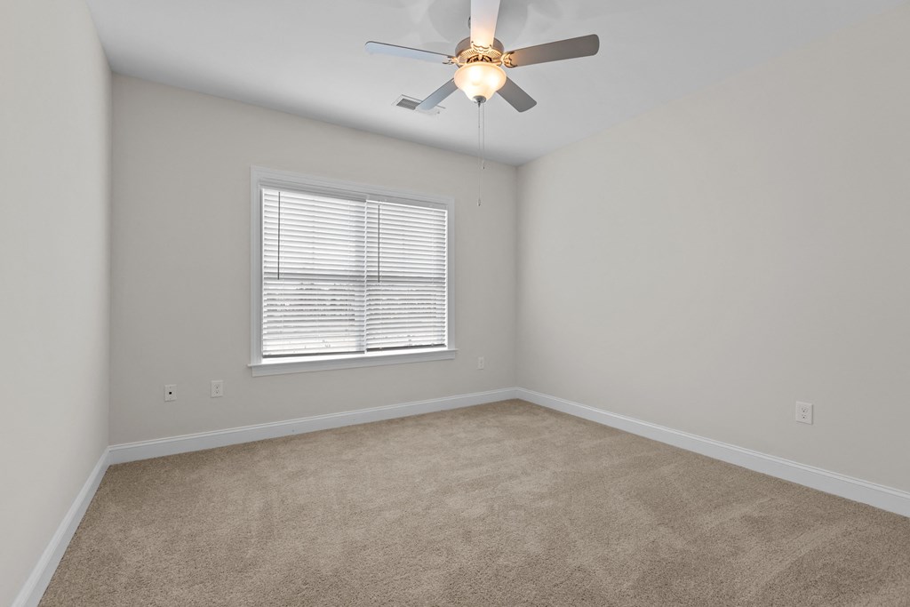 an empty room with a ceiling fan and a window