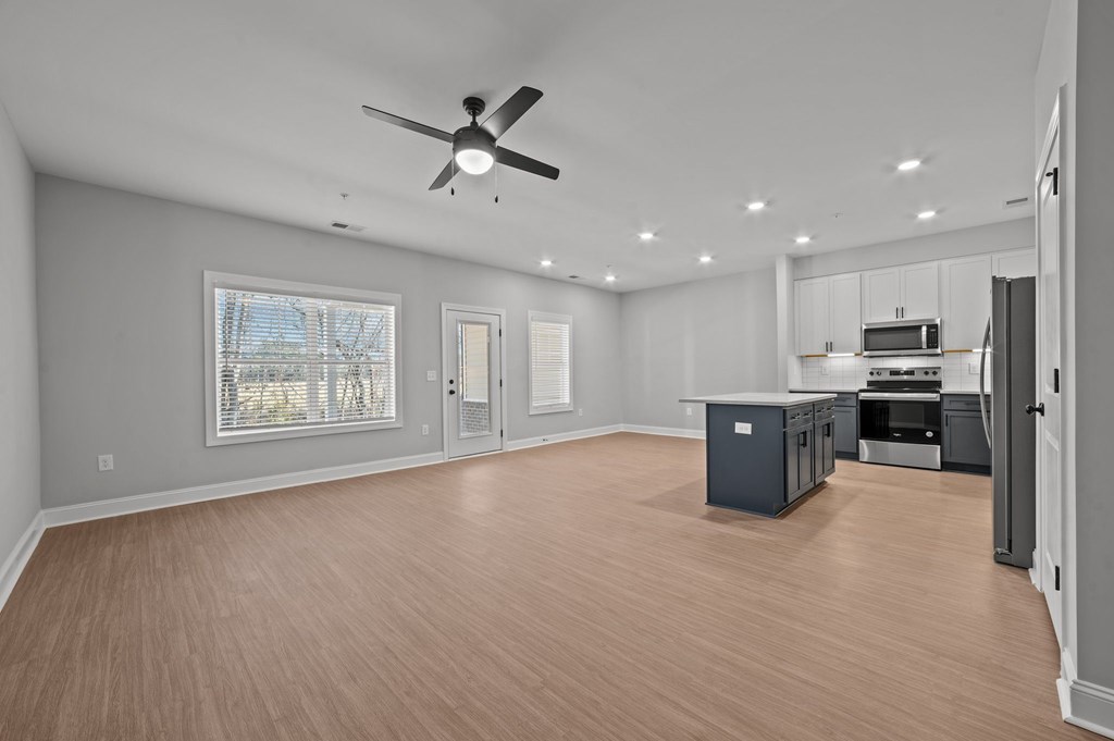 A spacious room with a ceiling fan and wooden flooring.