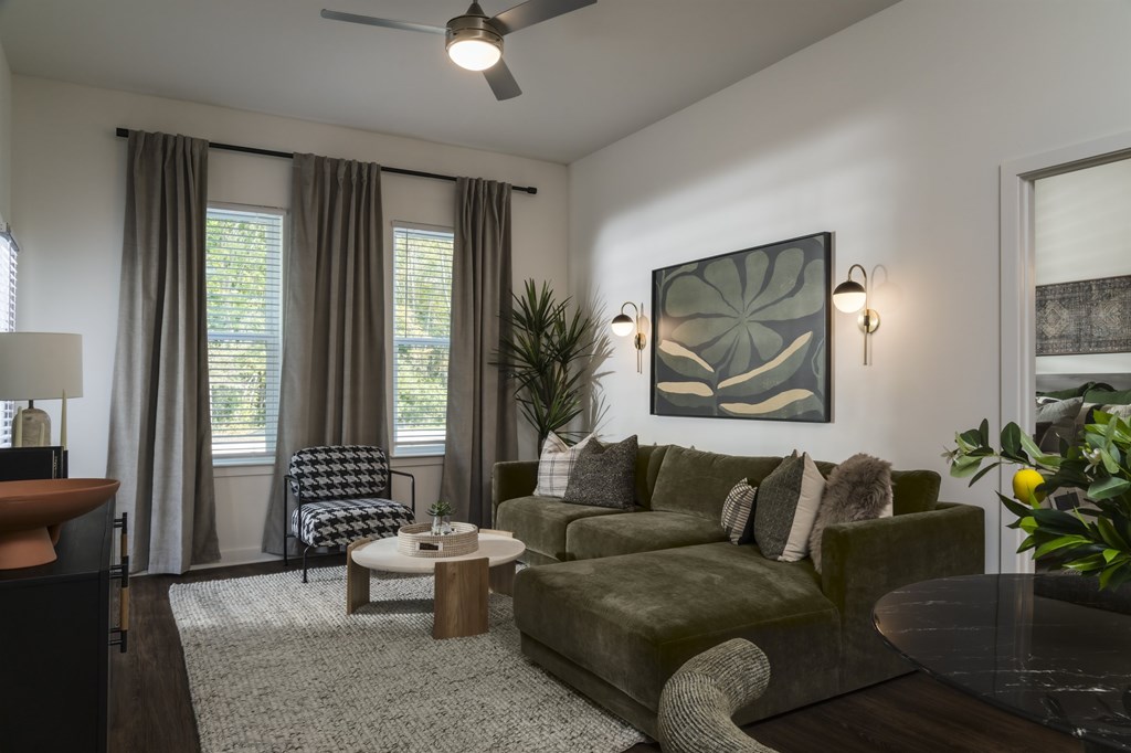 A living room with a green couch and a ceiling fan.