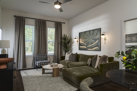 A living room with a green couch and a ceiling fan.