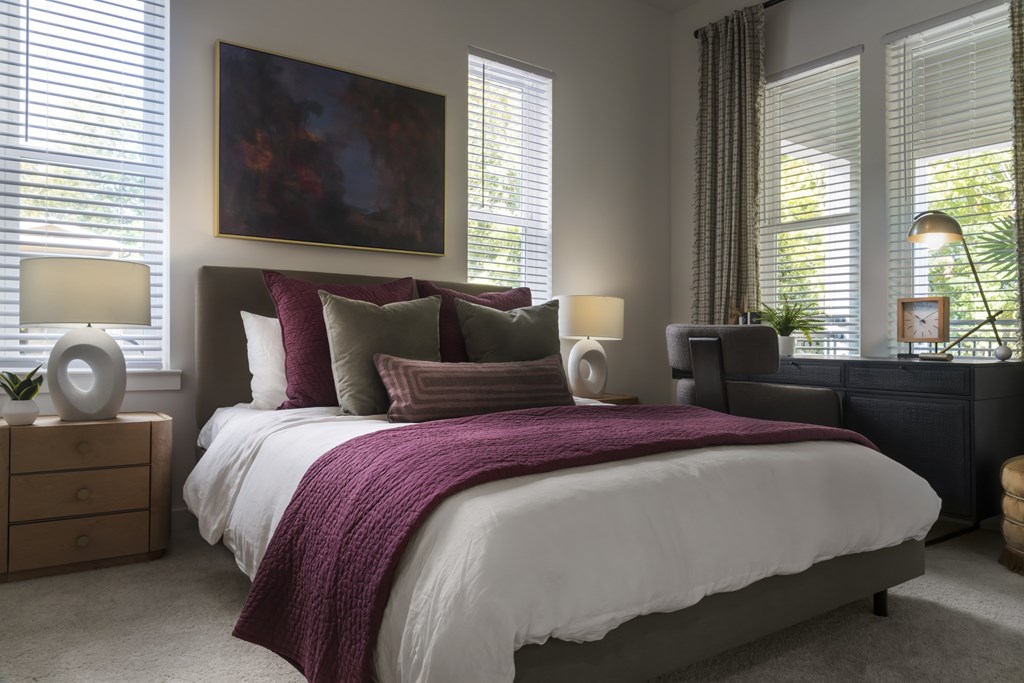 A bedroom with a large bed and a painting on the wall.