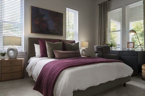 A bedroom with a large bed and a painting on the wall.