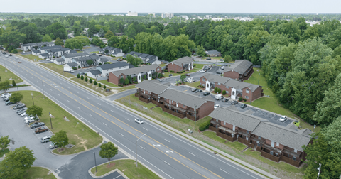 A road with cars and houses on both sides.