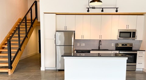 A kitchen with a staircase on the left side.