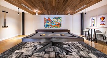 A pool table in a room with a wooden ceiling and a black and white rug at Judson Mill Lofts, Greenville, SC 29611