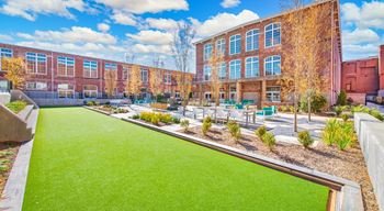 A green lawn in front of a red brick building at Judson Mill Lofts, Greenville, South Carolina
