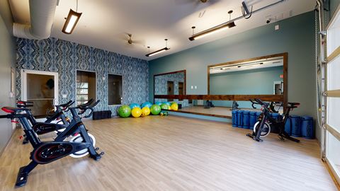 a fitness room with exercise bikes and a mirror