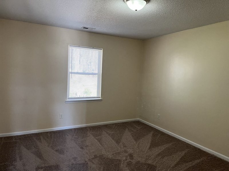 an empty room with a window and a carpet