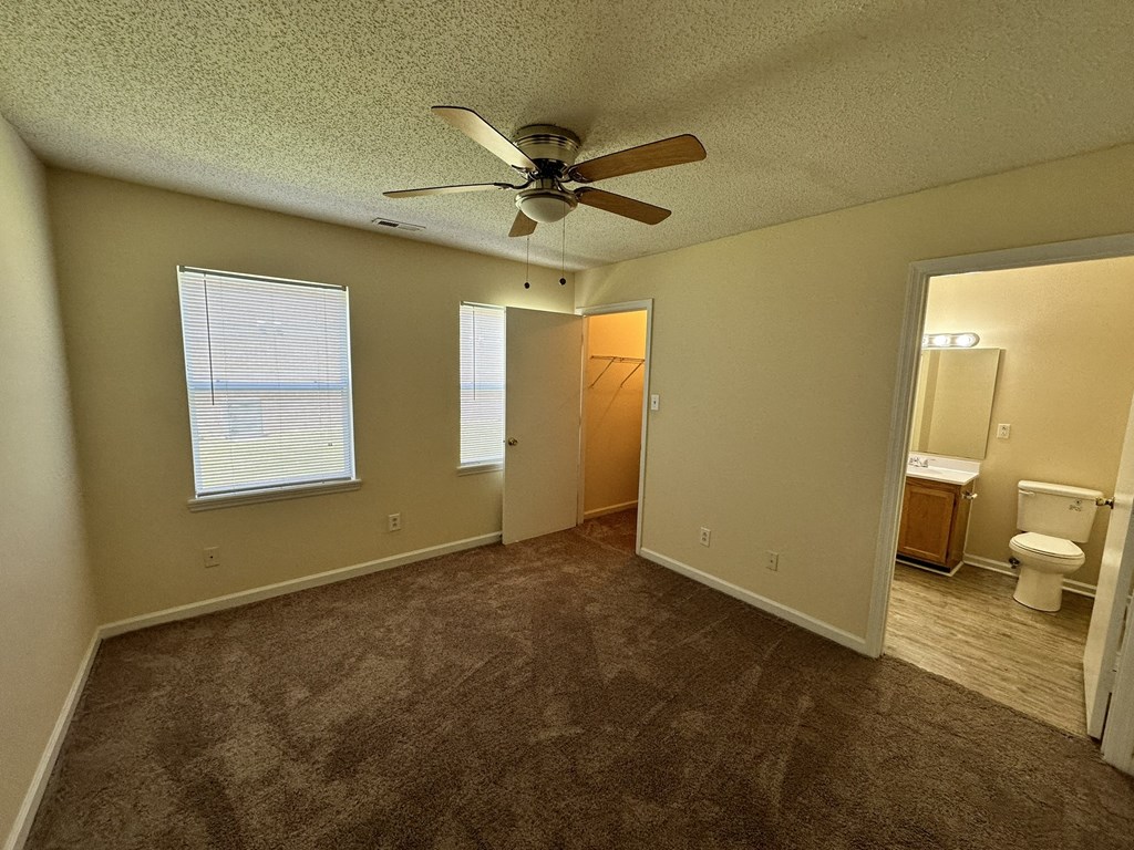 an empty living room with a ceiling fan and a bathroom